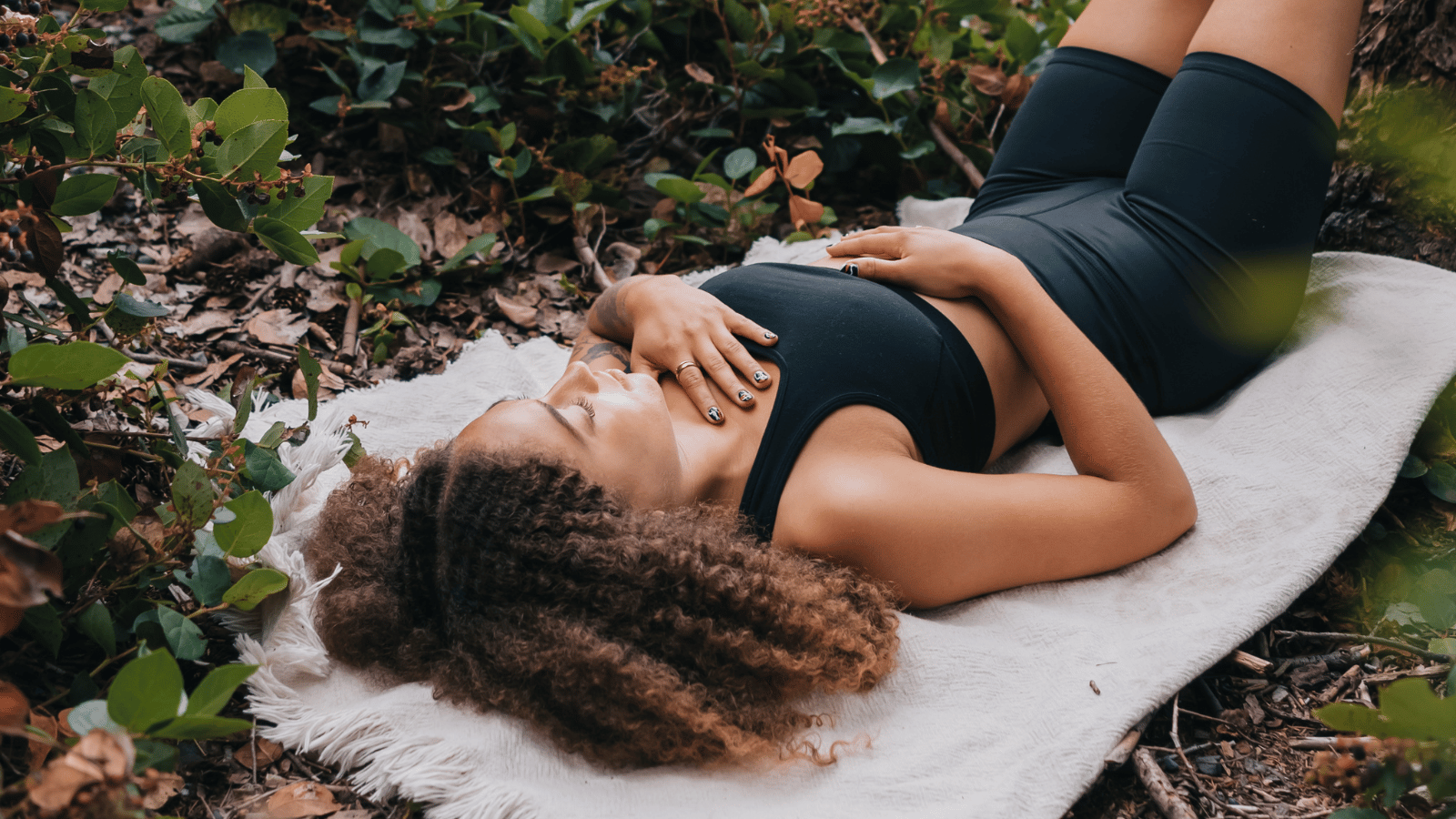 A woman practices mindful breathing meditation with hands placed on her chest and belly, demonstrating the relaxing body scan technique for deeper awareness and stress relief.